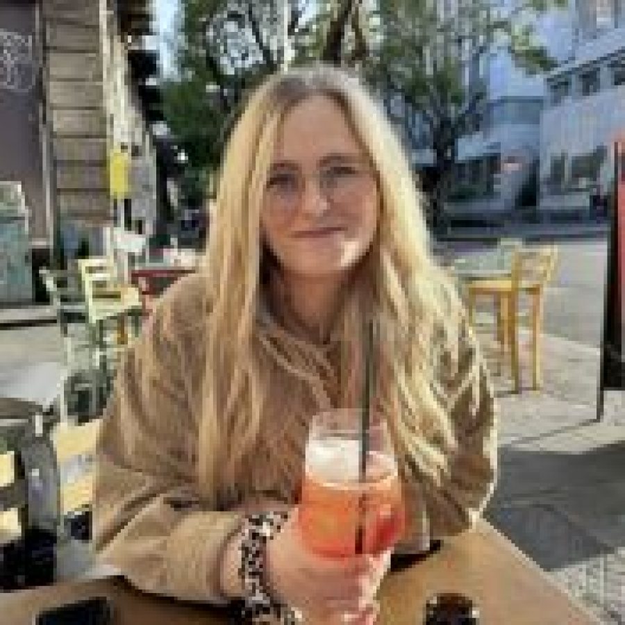 Eine Kundin sitzt draußen mit einem Getränk und berichtet über ihre Erfahrungen im Coaching für Frauen