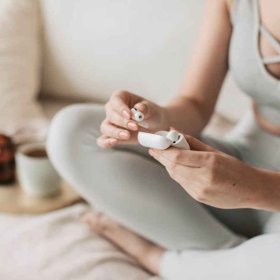 Frau hält kabellose Kopfhörer in der Hand – Meditaton und Mindset-Arbeit im Coaching für Frauen